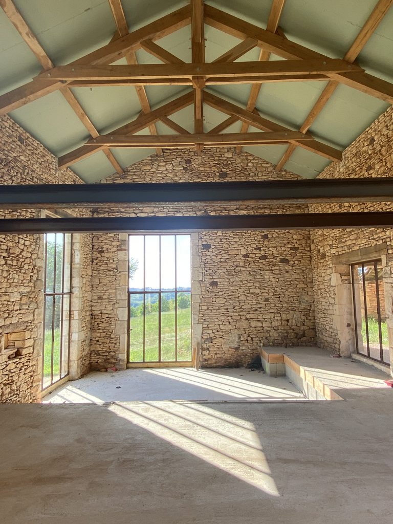 Réhabilitation intérieure d’une grange avec charpente bois et murs en pierre – Lot